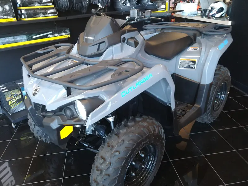 Front view of a gray and blue Can-Am Outlander 570 ATV on a tiled showroom floor