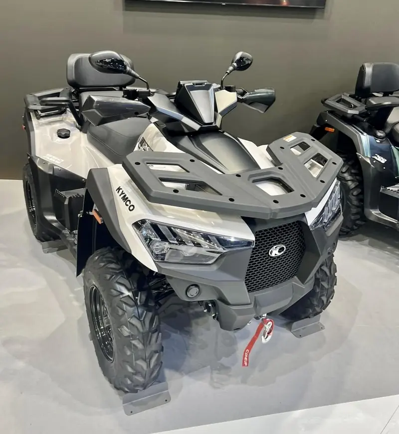 Silver and black Kymco MXU 700 ATV with a passenger seat on a trade show floor